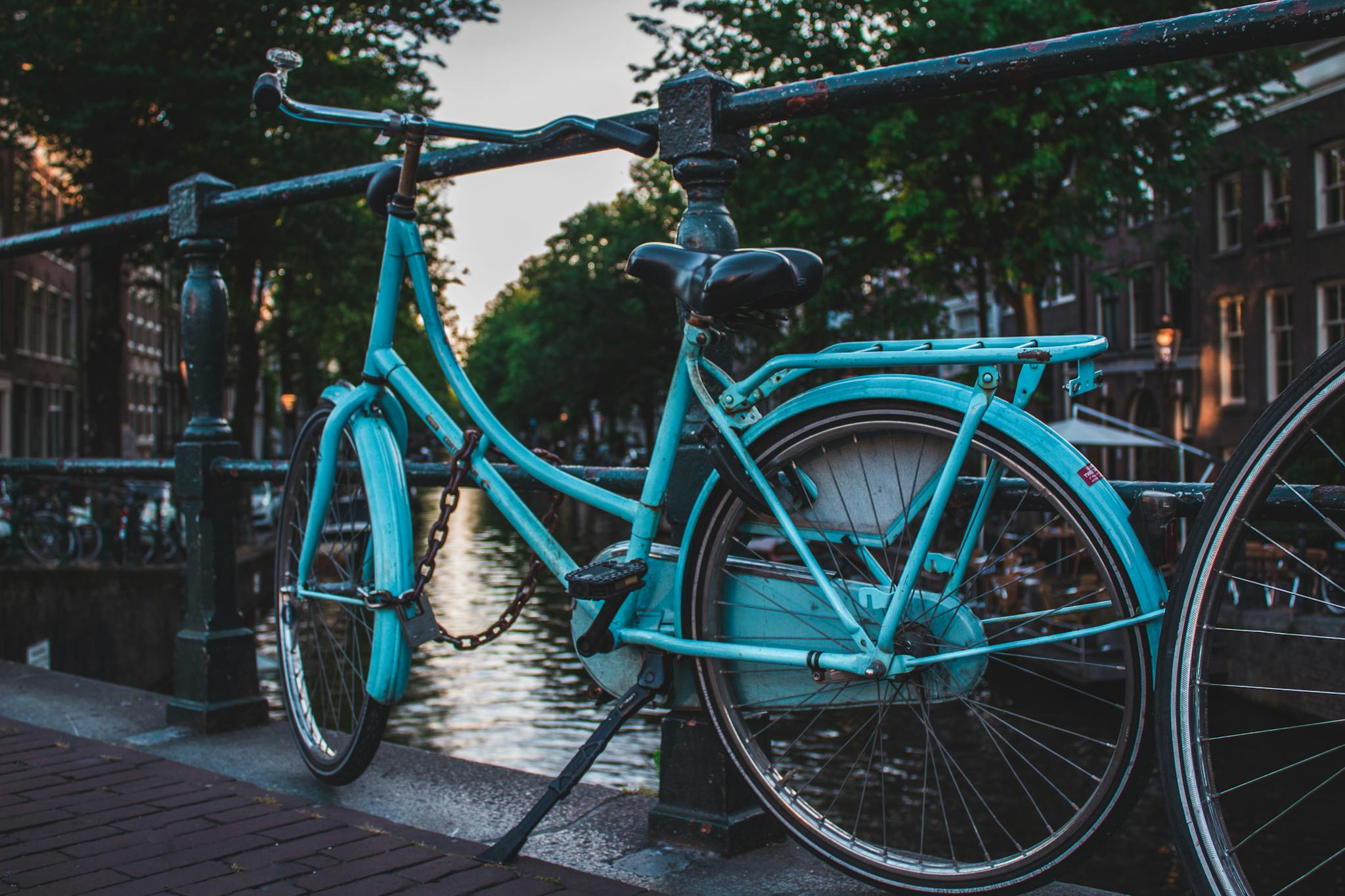A classic blue bicycle parked on a canal bridge in Amsterdam, Netherlands, showcasing urban charm.