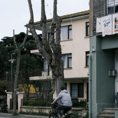 A cyclist rides past classic architecture in an İstanbul street, capturing urban charm and tranquility.