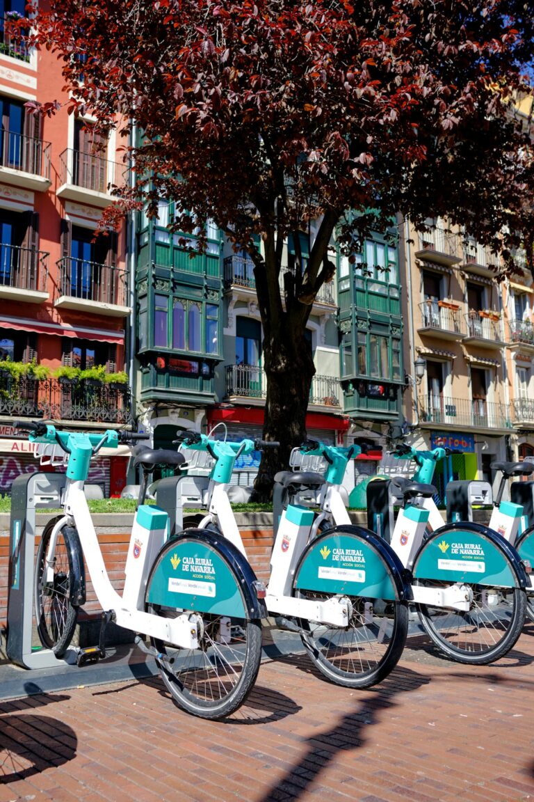 Colorful row of rental bicycles at a city center station with vibrant architecture.